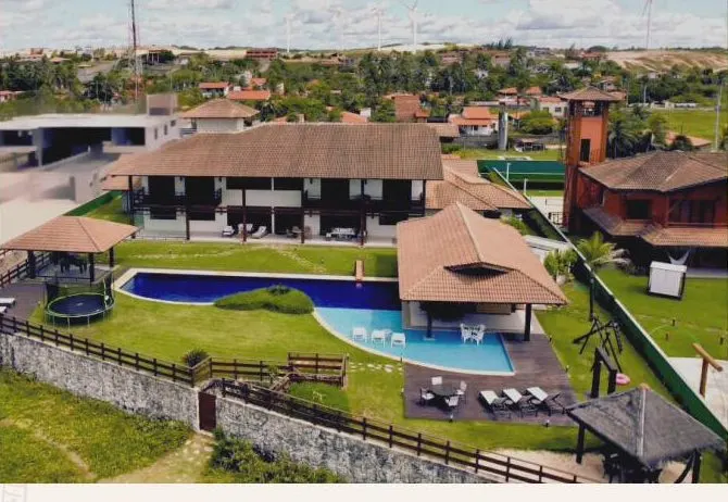 Vista aérea da Casa Amarela com piscina e gramado à beira-mar